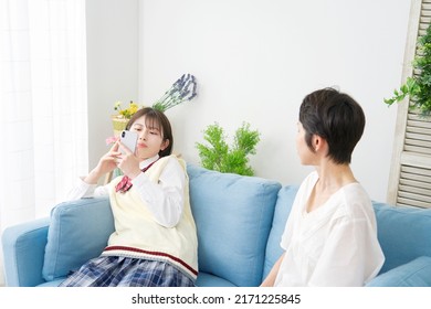 Asian High School Student Using The Smartphone Front Of Her Mother