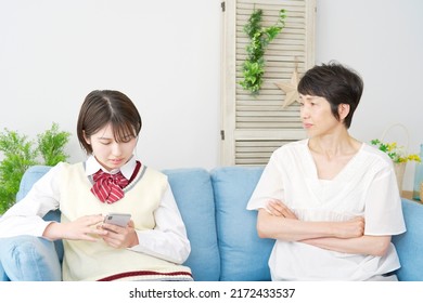 Asian High School Student Using The Smartphone Front Of Her Mother At Home