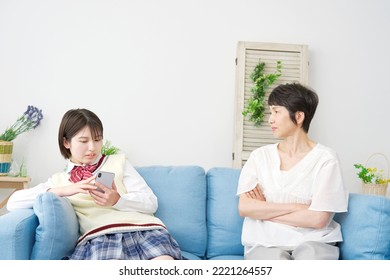 Asian High School Student Using The Smartphone Front Of There Mother At Home