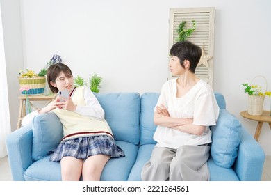 Asian High School Student Using The Smartphone Front Of There Mother At Home