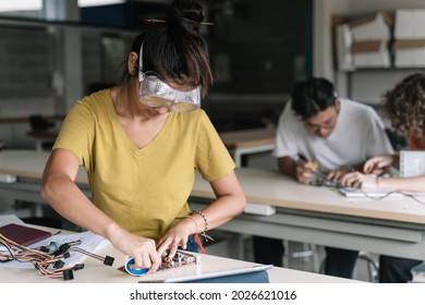 Asian High School Teenage Student Wearing Protective Goggles Working On Electronics Circuit Board In The Science Technology Workshop - Digital Innovation In Education