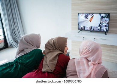 Asian hijab woman with friends lying on the bed enjoy watching the television for pass the time together - Powered by Shutterstock