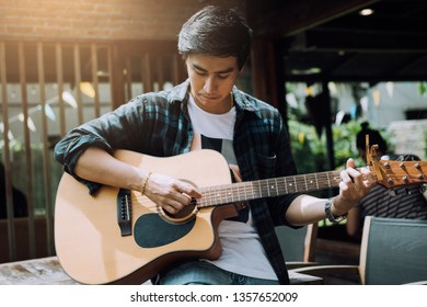 Asian Hipster Man Left Hand Catch Chord And Playing Music.