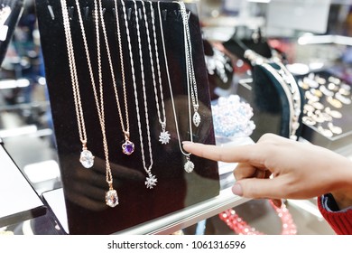 Asian Hipster Woman Chooses Jewelry In A Store And Looks At The Display Case