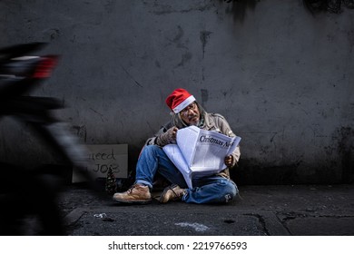 Asian Homeless Aged Man Upset Wearing Red Christmas Hat Sitting On Roadside Reading Newspaper About Politics And Economy, Aged Man With Beard Begging For Money, No Job. Society's Economic Problem.