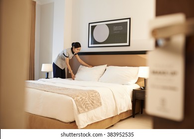 Asian Hotel Maid Making Bed, View From The Entrance Of The Room