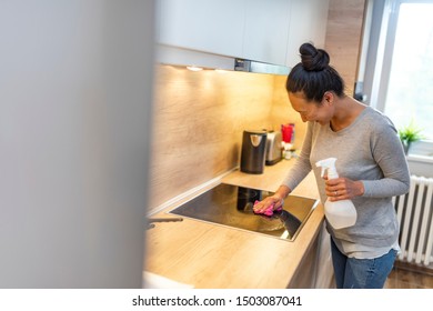 Asian Housewife Cleaning Furniture In Kitchen With Detergent. Glad Mature Asian Woman Wiping Surfaces At Home In Kitchen Interior. Woman Cleaning Kitchen. Woman Washing Kitchen Hood