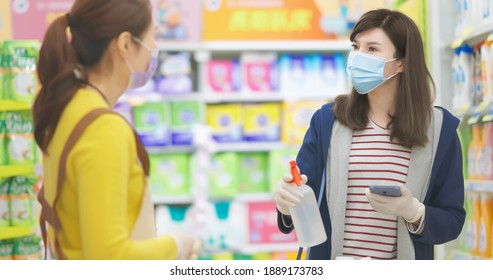 Asian Housewife Wearing Face Mask And Gloves Asks Seller Woman About Cleaning Supplies Information At Grocery Store During Virus Epidemic Outbreak