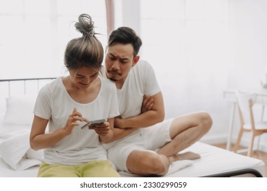 Asian husband peeking wife chatting on the phone if she might has an affair.