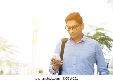 Asian Indian Business People Texting Using Smartphone While Walking To Office, Modern Urban Sunrise View.