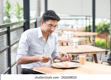 Asian Indian Businessman Eating Food At Cafeteria.