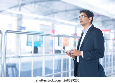 Asian Indian Businessman Using Tablet Computer While Waiting Train At Railway Station.