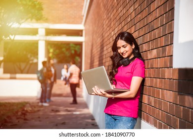 Asian Indian College Student In Focus Working On Laptop Or Reading Book While Other Classmates In The Background, Outdoor Picture In University Campus