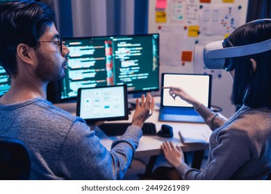 asian and Indian Developer  devops team testing  virtual reality coding promgram app at night in office