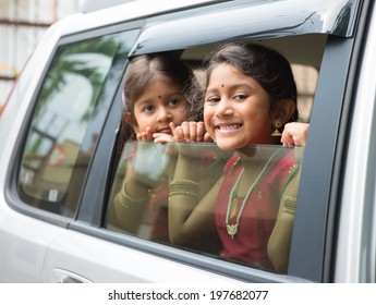 Asian Indian Family Going To A Vacation. Happy Children Sitting Inside Car With Window Open Looking Out. 