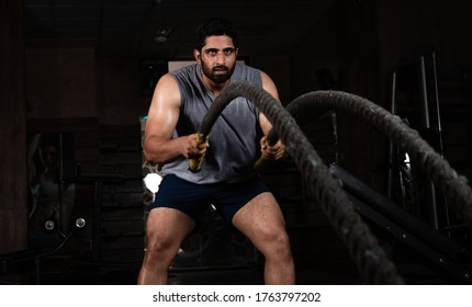Asian Indian Man Doing Exercise With Battle Rope In Gym