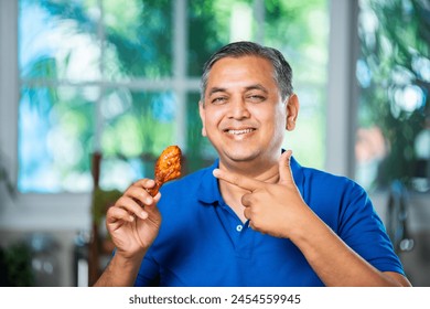 Asian indian mid age man eating fried chicken leg piece - Powered by Shutterstock