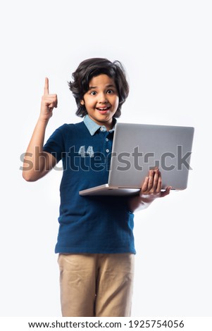 Asian Indian school kid holding and using laptop while standing against white background