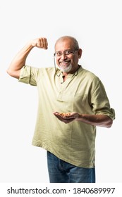 Asian Indian Senior Adult Or Old Man Showing Dry Fruits Like Cashew, Almond Or Walnut - Healthy Eating Concept