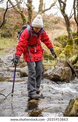 Asian Indian woman hiker in waterproof clothing, hiking in Gwydyr Forest, Snowdonia, Wales, UK