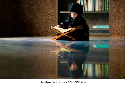 Asian Indonesian Muslim Kid Is Reading The Quran. The Quran Is Indicated As The Guided Book For All Muslim And It Is Direction  To Be On The Heaven Of God.Mosque,Islam,religion And Knowledge Concept.