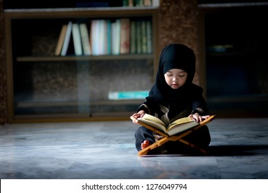 Asian Indonesian Muslim kid is reading the Quran. The Quran is indicated as the guided book for all Muslim and it is direction  to be on the heaven of God.Mosque,Islam,religion and knowledge concept.