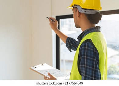 Asian inspector checking structure of new property and taking note in the clipboard for review and fix the house before sell to client - Shutterstock ID 2177564349