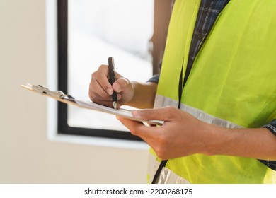 Asian inspector checking structure of new property and taking note in the clipboard for review and fix the house before sell to client - Shutterstock ID 2200268175