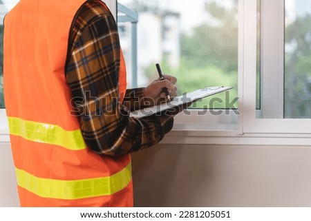 Asian inspector checking structure of new property and taking note in the clipboard for review and fix the house before sell to client