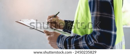 Asian inspector checking structure of new property and taking note in the clipboard for review and fix the house before sell to client