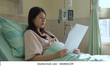 asian japanese pregnant woman patient in bed is reading diagnosis paper with serious face and worried about her health. - Powered by Shutterstock