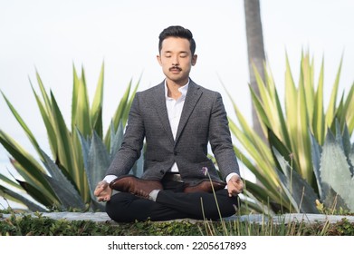 Asian Japanese Young Man Wearing A Suit With No Tie Meditating Outdoors With Eyes Closed