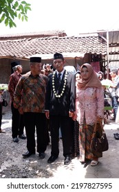 Asian Javanese Muslim Groom Walks Accompanied By His Parents And Extended Family, Wearing A Black Coat And Skullcap With A Jasmine Necklace : Jepara, Indonesia : April 16, 2019