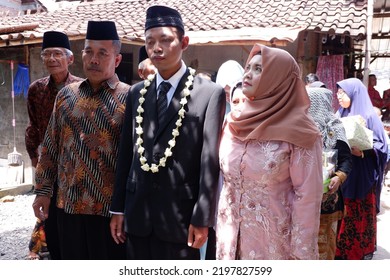 Asian Javanese Muslim Groom Walks Accompanied By His Parents And Extended Family, Wearing A Black Coat And Skullcap With A Jasmine Necklace : Jepara, Indonesia : April 16, 2019