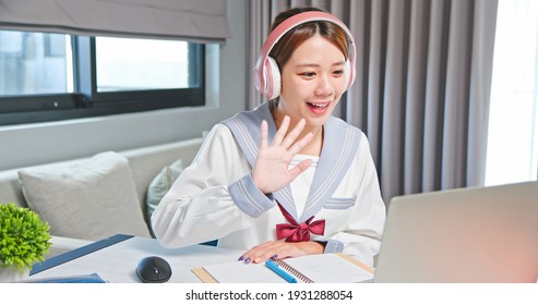 Asian Junior High School Female Student Is Learning And Looking Online Course Through Laptop With Hello Gesture At Home