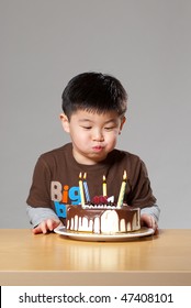 An Asian Kid Blowing Candles On His Birthday Cake