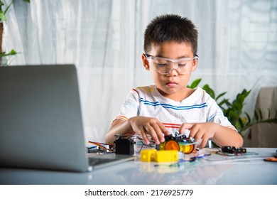 Asian Kid Boy Assembling Wheel Into Arduino Robot Car Homework, Little Child Trying Assemble Build Wheel To Car Toy, Creating Electronic AI Technology Workshop Online School Lesson