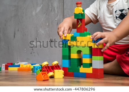 Asian kid boy building house from plastic blocks