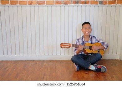 Asian Kid Boy Child Playing Guitar Ukulele At Home. Children Leisure Activity