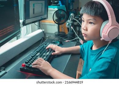 Asian kid is coding and scripting program on on his game streaming desktop computer with headphone on. - Shutterstock ID 2166944819