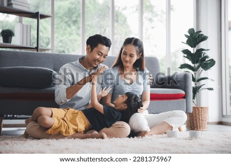 Asian kid cute girl lying on mom and dad happy living relaxing with young mom and dad at home, Happy young family living concept