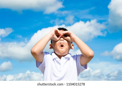 (Asian kid) Cute white shirt kid boy are looking blue sky by his hand camera and  taking shock face.