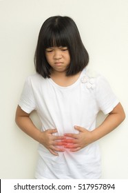 Asian Kid Girl Hands On Her Stomach With Red Spot As Suffering On Stomachache. Child Suffer From Chronic Diarrhea,Digestive Disorders, Stomach Pain,Crohn’s Disease, Gastroesophageal Reflux Disease