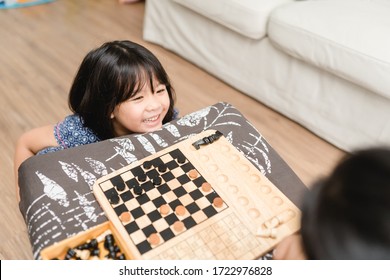 Asian Kid Girl And Mother Stay At Home Lockdown From Covid-19 Coronavirus Crisis Are Playing Chess While Spending Time Together At Home.Smart Kid Home School Kid With Mom.Stay Home Stay Safe With Mom.