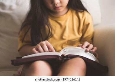 Asian Kid Girl Read Bible Study.Worship At Home.Sunday School.Bible On Kid Hands.Family Christian ,Reading Bible Study.Hands Holding On A Holy Bible.faith, Spirituality And Religion.child Pray Online.