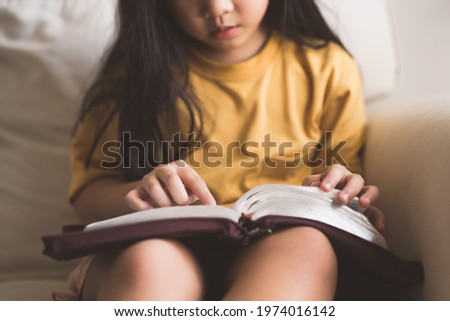 Asian kid girl read bible study.Worship at home.Sunday school.Bible on kid hands.Family christian ,Reading bible study.Hands holding on a Holy Bible.faith, spirituality and religion.child Pray online.