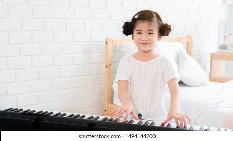 Asian kid girl is training to play an electric piano. Is an activity that trains emotional skills And the body well Study at home or music school Music. good mental health and good mood. copy space