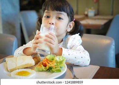 Asian Kid Having A Healthy Breakfast In The Morning. (focus On A Glass Of Milk)            