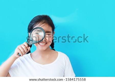 Asian kid holding Magnifying glass over blue background,copy space.