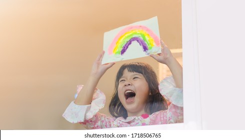 Asian Kid Home School Girl Painting Showing Rainbow During Covid-19 Coronavirus Stay At Home For Free From Lockdown At Home.Social Distancing, New Normal.Freedom Hope During Coronavirus Covid19.